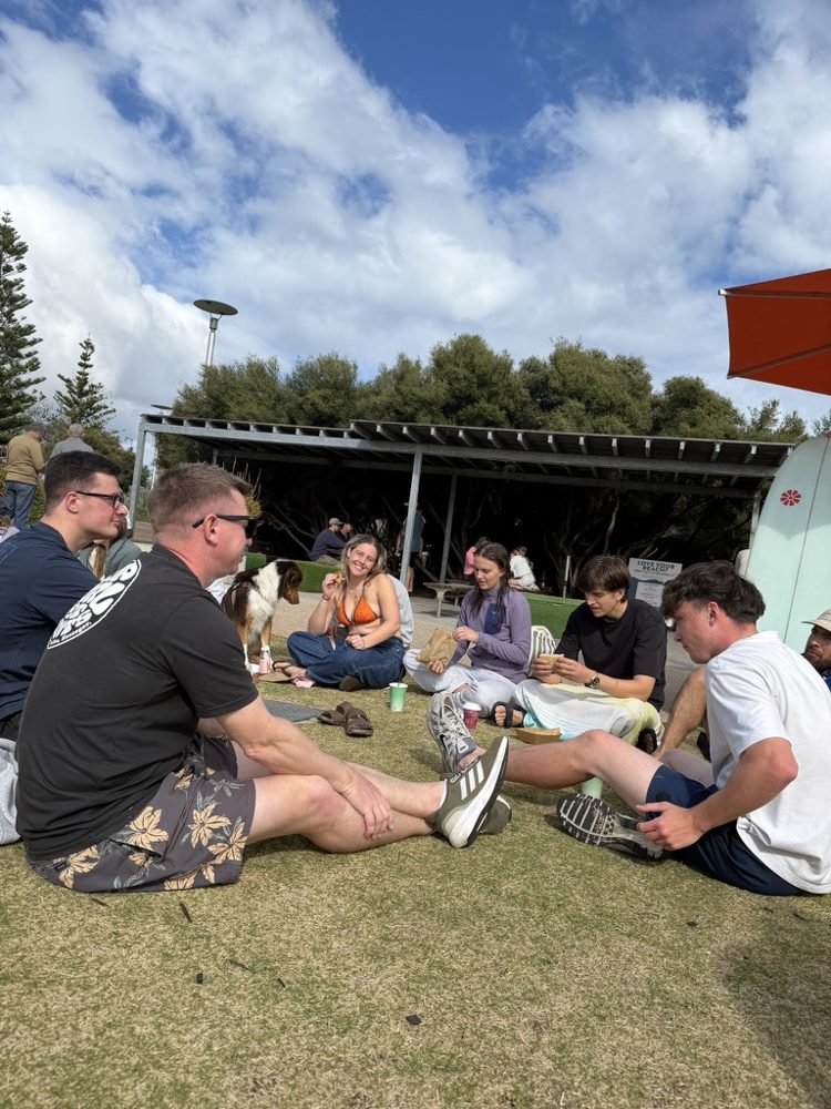 Newbies sitting on the grass together after a surf social