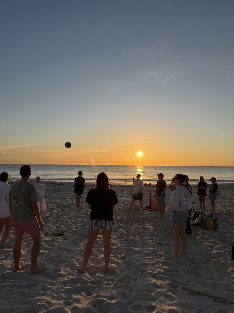 Newbies passing a ball on the beach at sunset